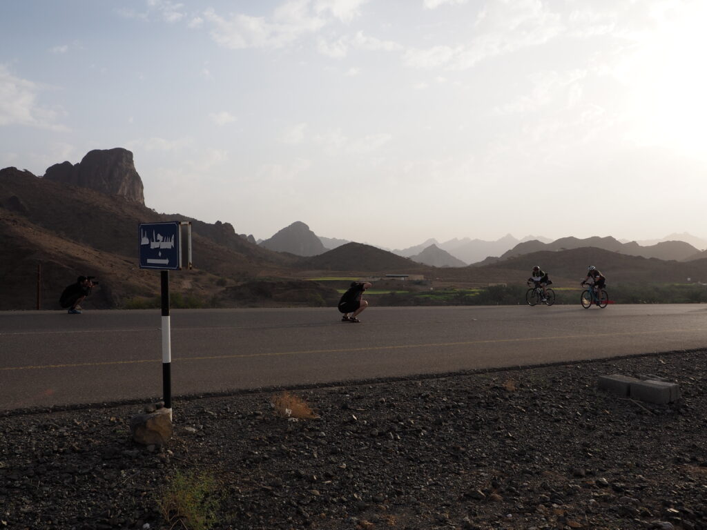 Video maker Pehuen Grotti and photographer Christian Lartillot on a desert road filming and photographing two cyclists.